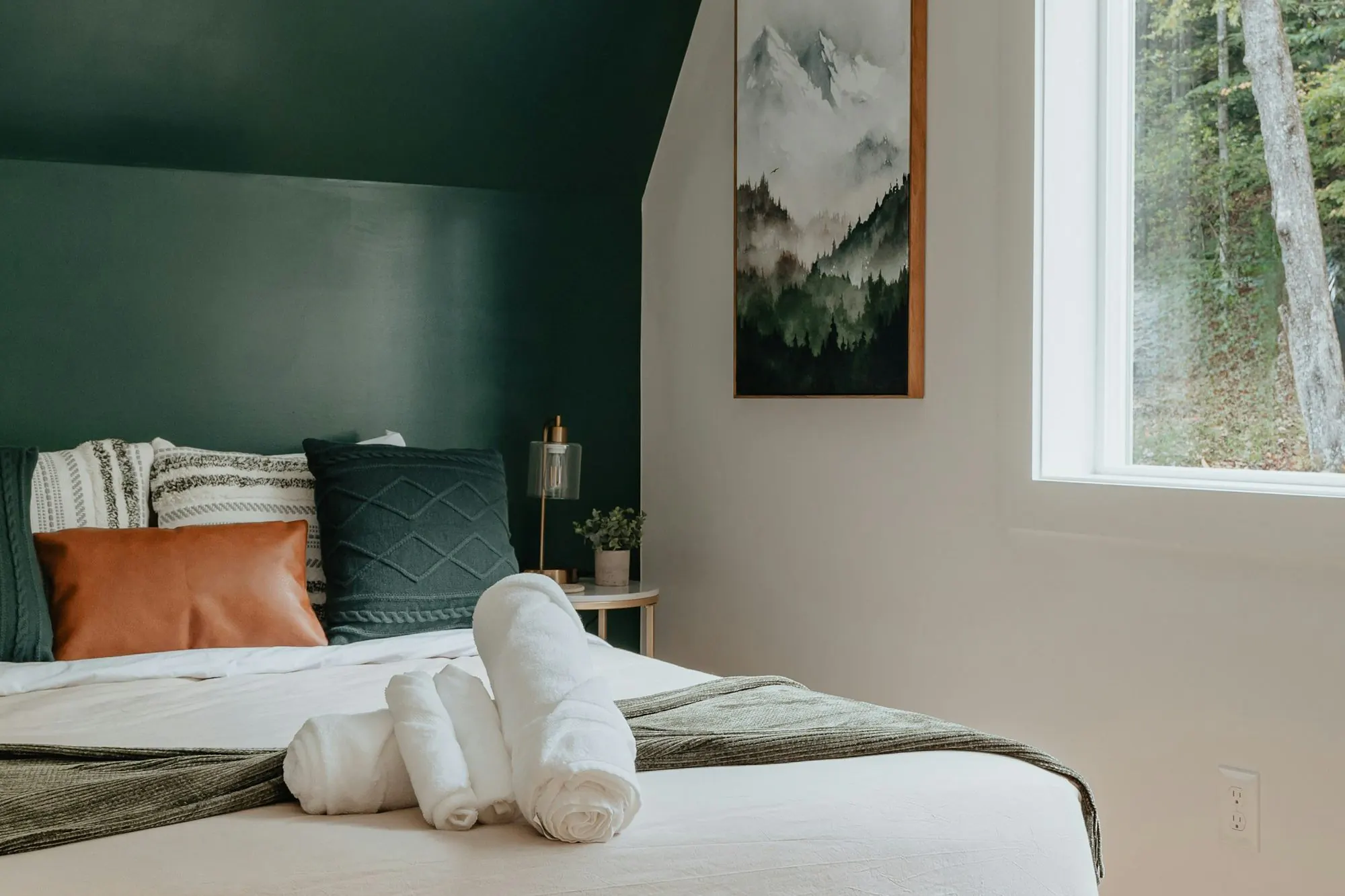 Freshly made guest bed with rolled towels