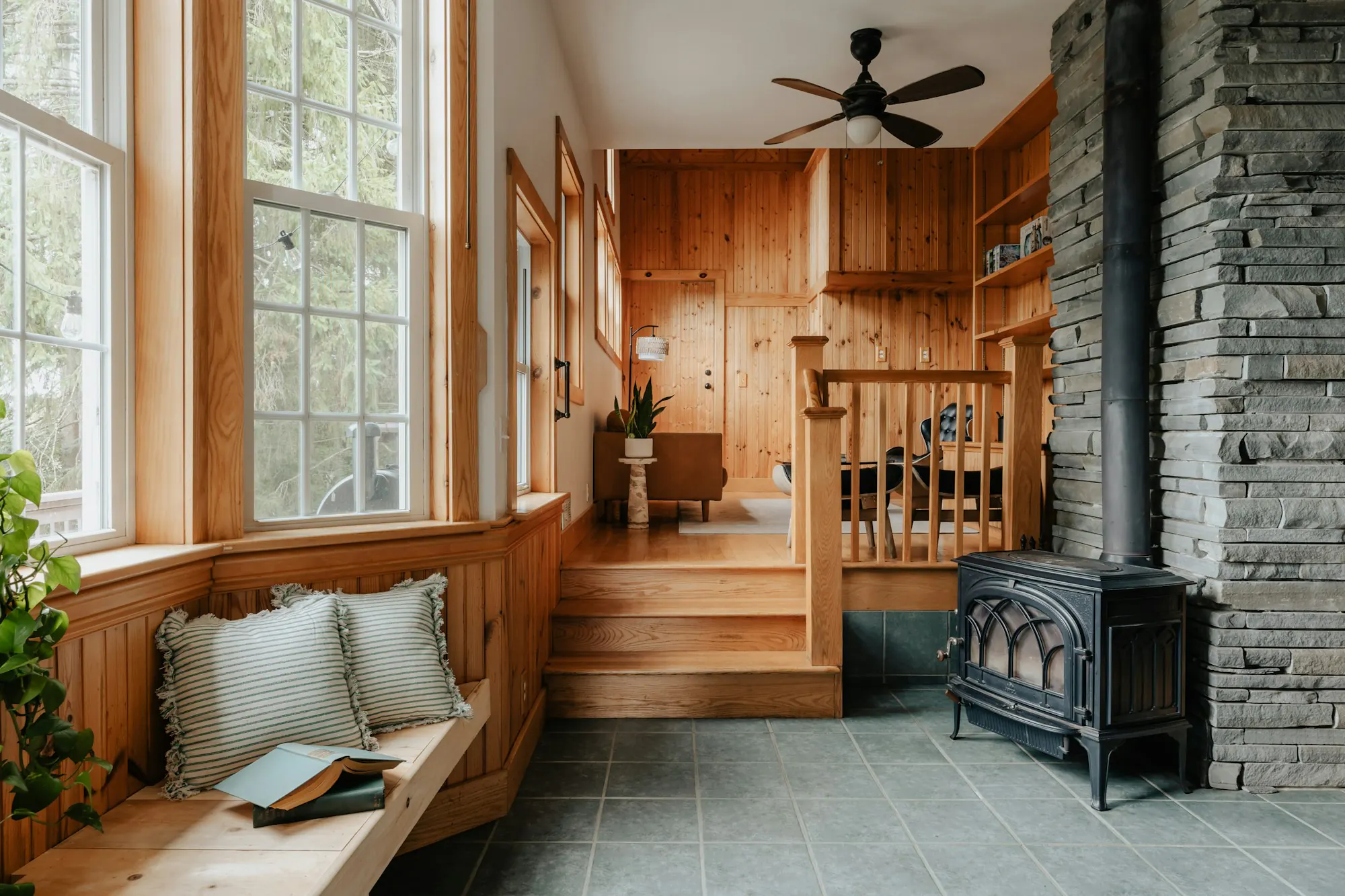 Cabin den with a stone wall, wood stove and window seat